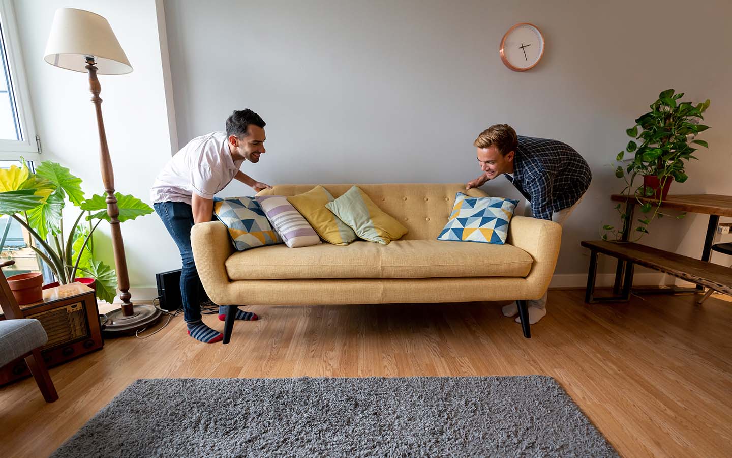 Young male couple move living room sofa