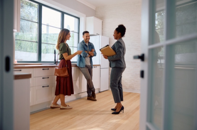 Happy real estate agent and a couple in the kitchen of a new house